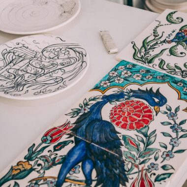 Colorful ceramic tile art featuring a peacock and floral patterns on a table.